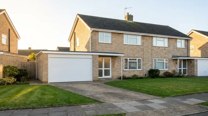 Semi detached brick home in Basildon with a white roller garage door and neat front lawn