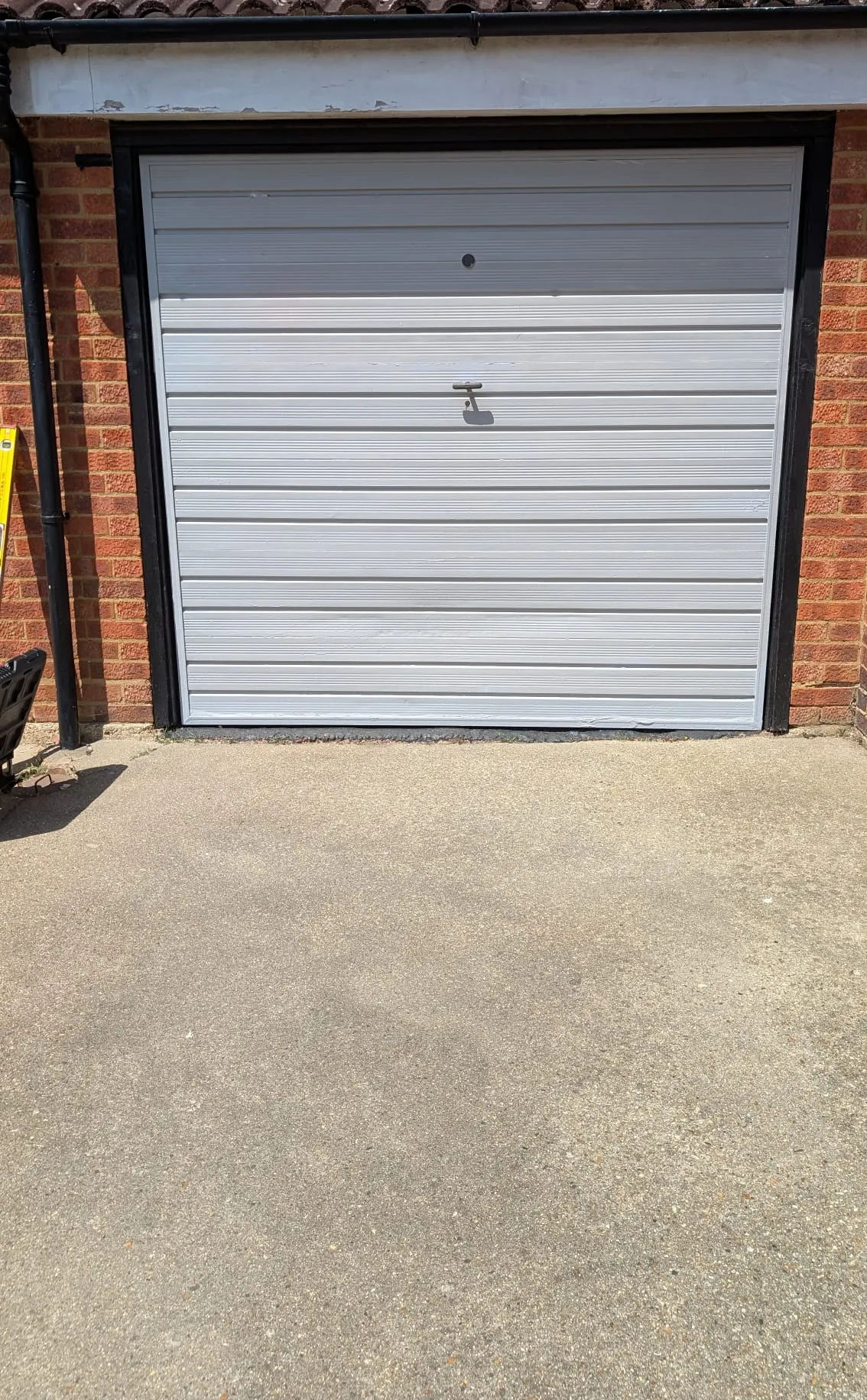 Before: old white manual roller garage door on the same brick garage