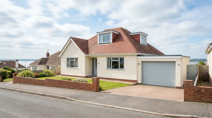 Chalet style home in Benfleet with a light grey roller garage door and estuary views behind