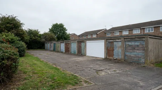 Communal garage block in Harlow with one smart new roller door among older doors