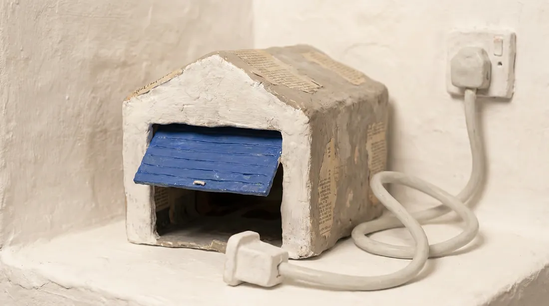 Papier mache garage sculpture with a single plug reaching to one wall socket